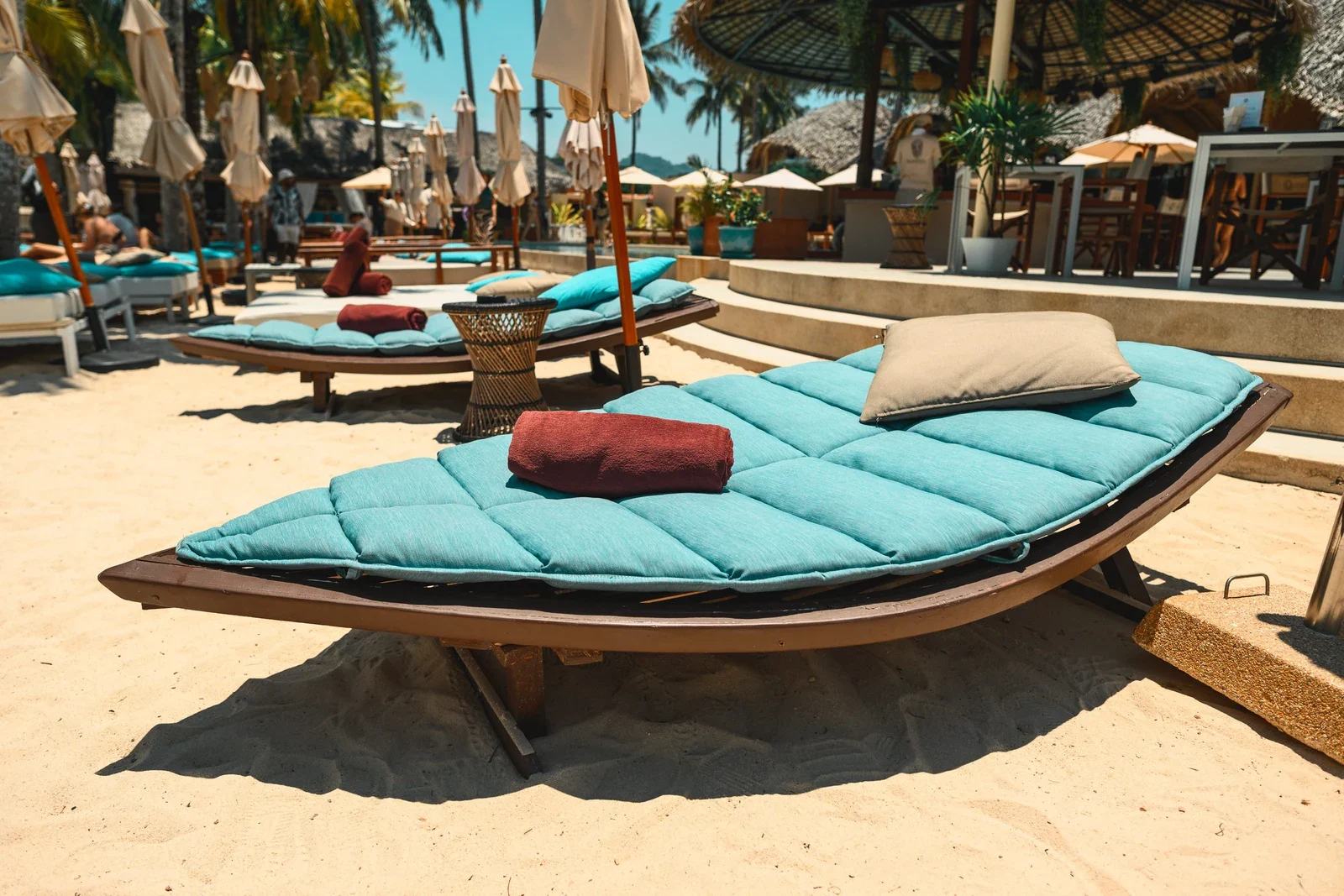 Двойные лежаки с бирюзовыми матрасами на песке Carpe Diem Beach Club