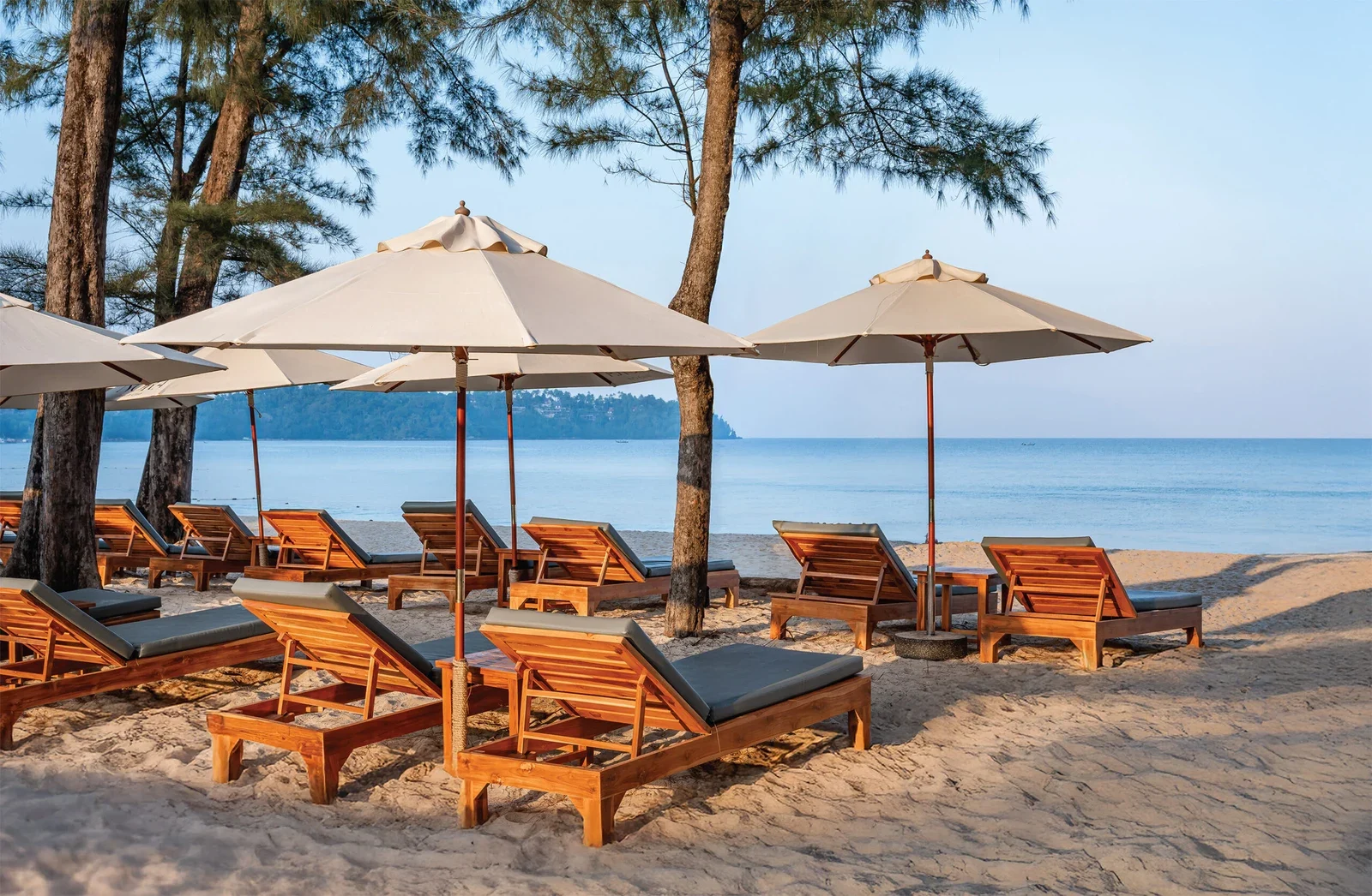 Деревянные шезлонги NORA Beach Club под светлыми зонтами на пляже Банг Тао