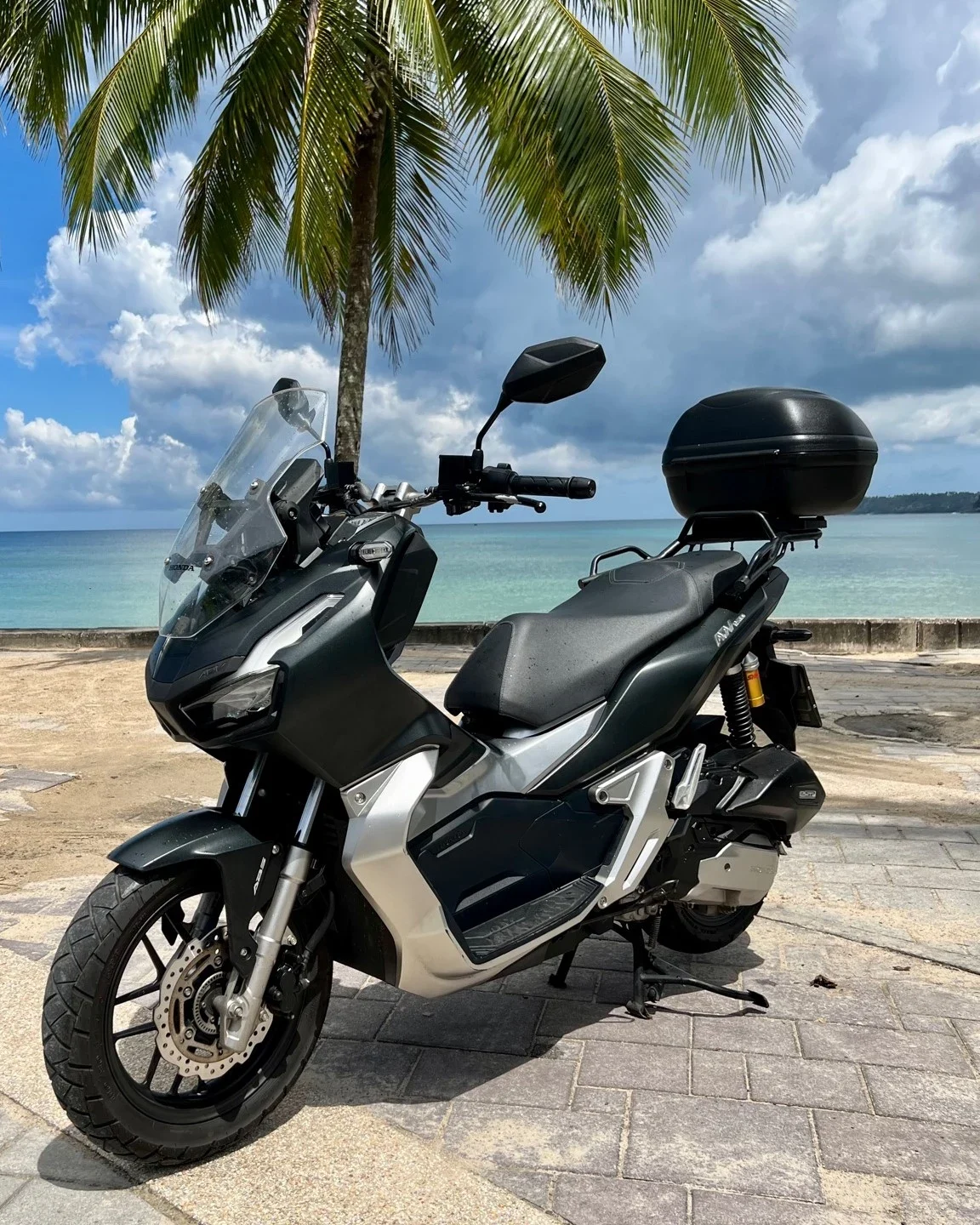 Скутер Honda ADV 150 с кофром припаркован на набережной у моря среди пальм на Пхукете