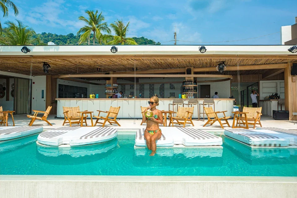 Бассейн FUGA Beach Club с белыми лежаками напротив открытого бара