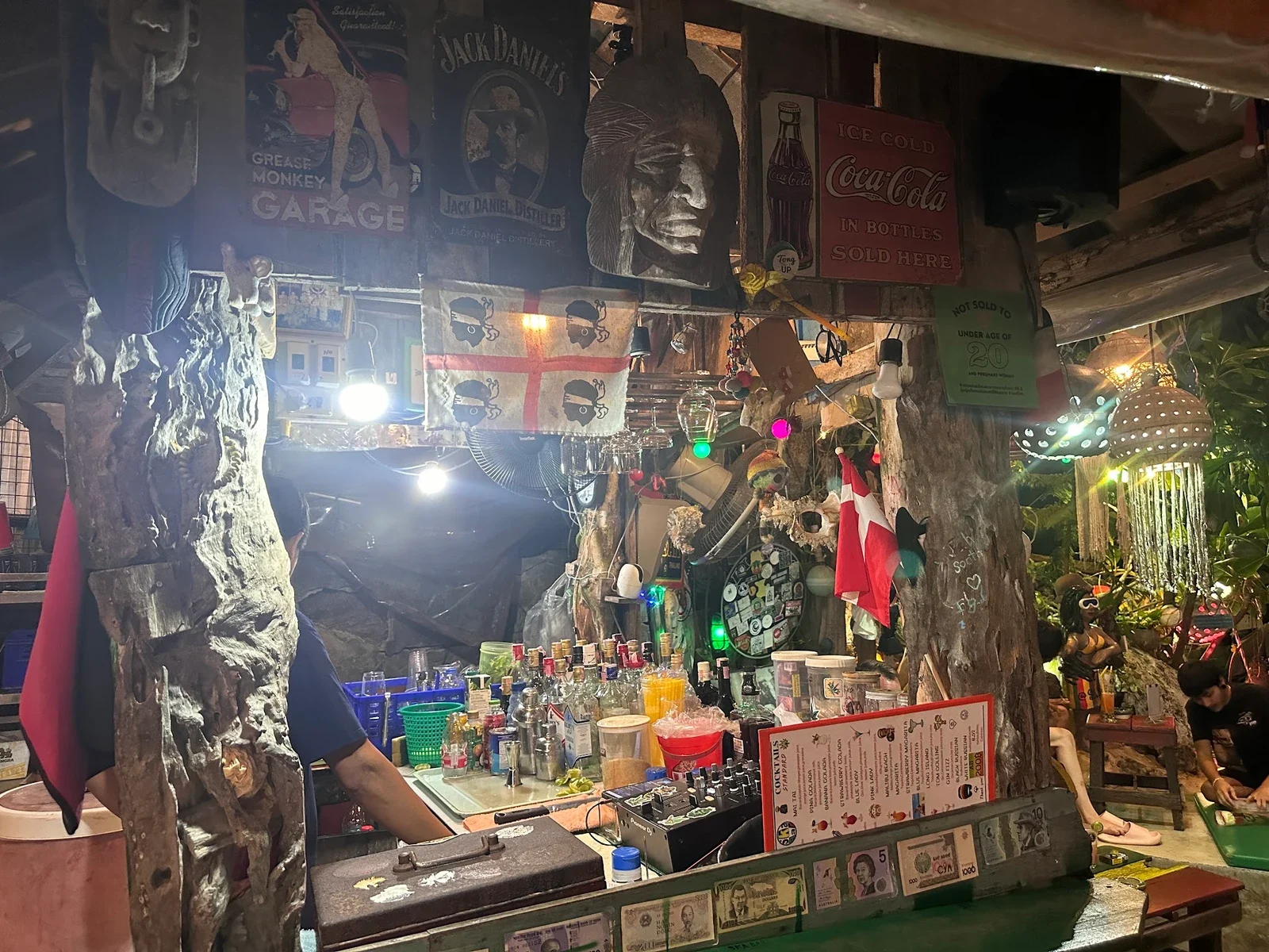 Барная стойка Ska Bar с бутылками, жестяными вывесками, флагами и купюрами на кромке стойки