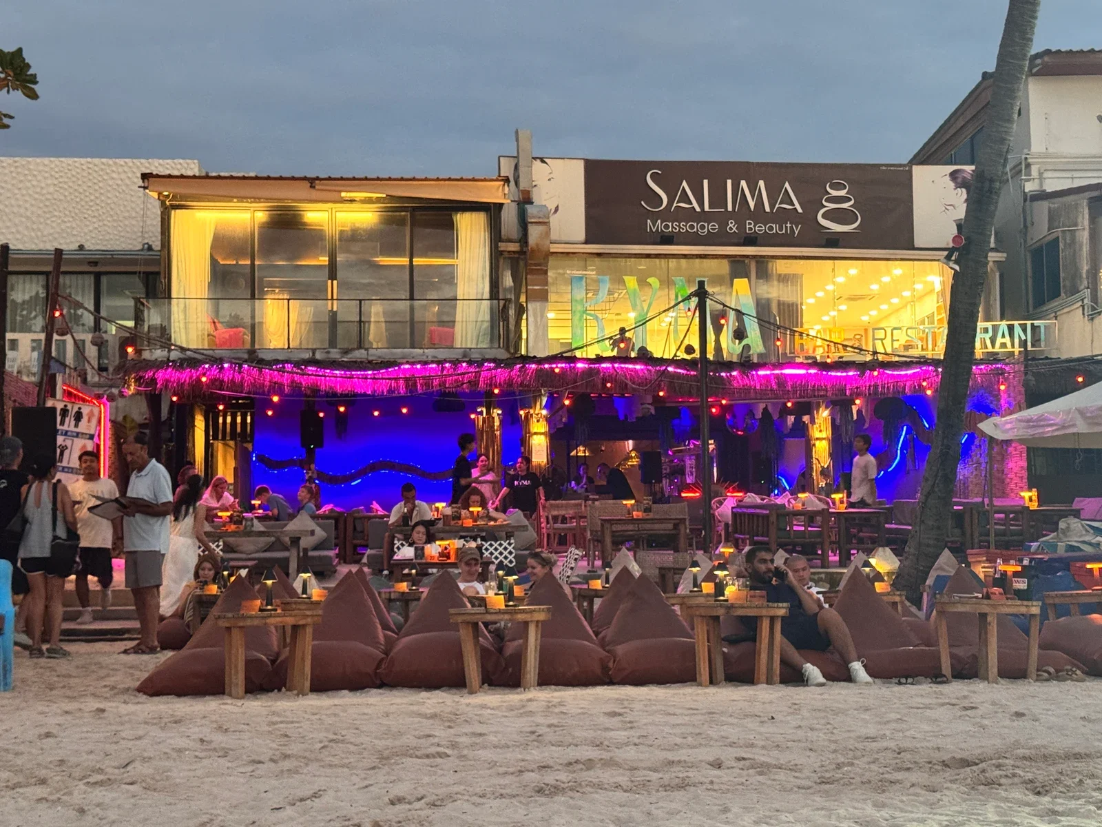 Фасад KYMA Beach Bar с мягкими креслами и низкими столиками на песке