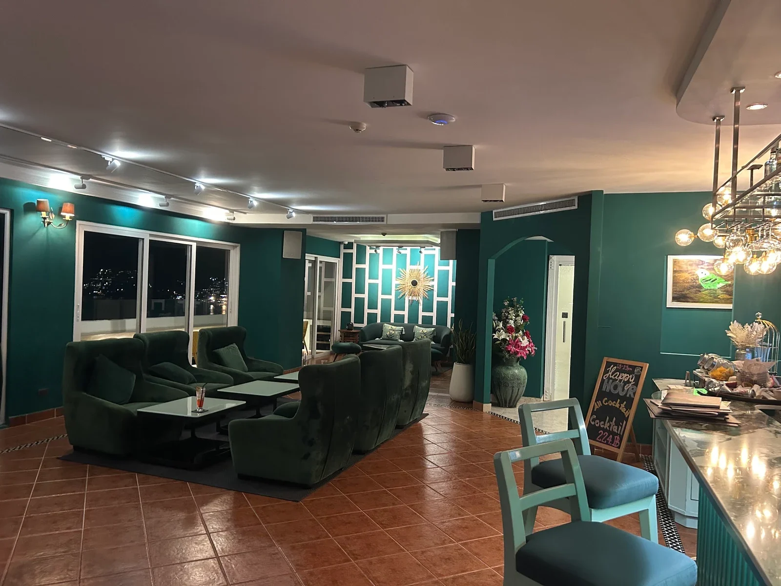 Внутренний зал Andaman Sky Lounge: зелёные диваны, терракотовая плитка и барная стойка