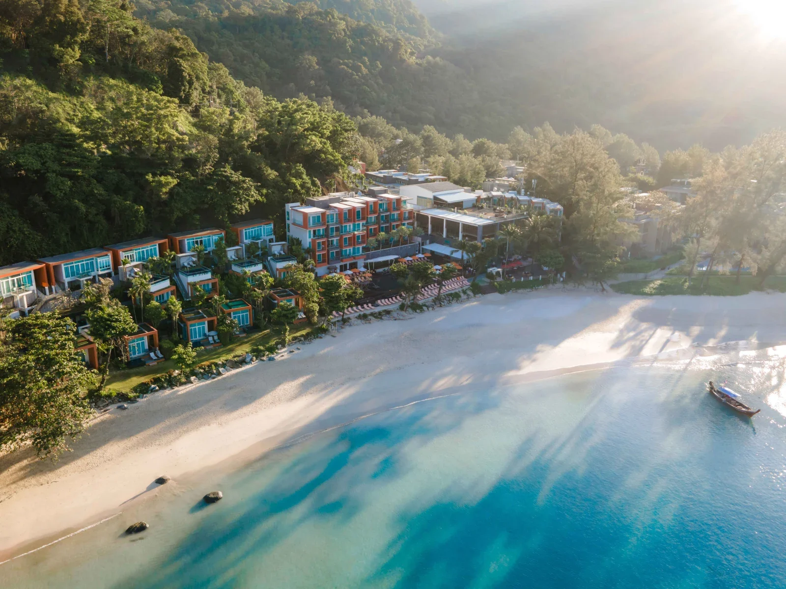 Вид сверху на Novotel Phuket Kamala Beach: оранжевые корпуса и виллы на лесном склоне у белого пляжа и бирюзовой воды