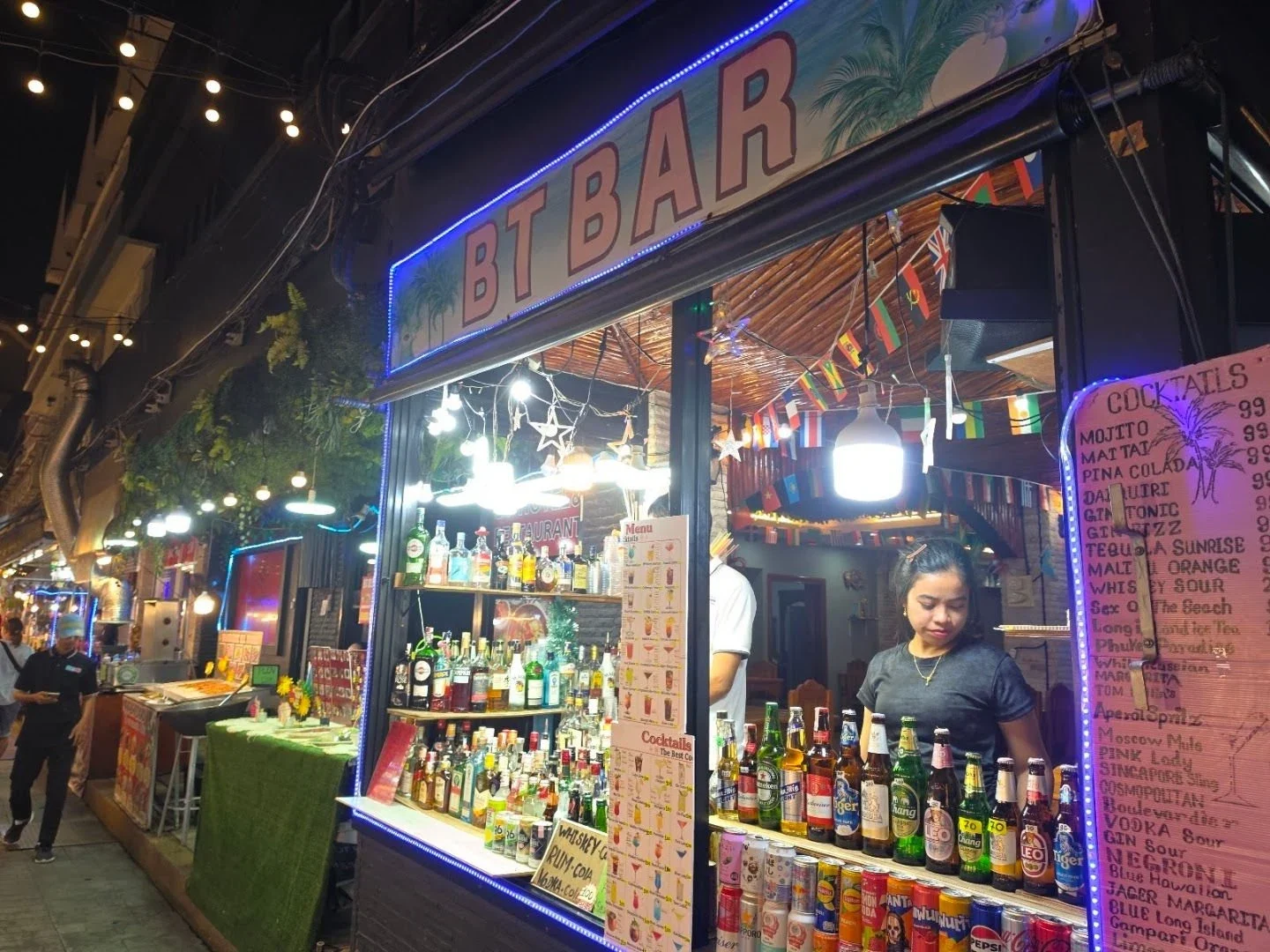 Продавщица готовит напитки у открытой барной стойки на вечернем рынке Kata Walking Street