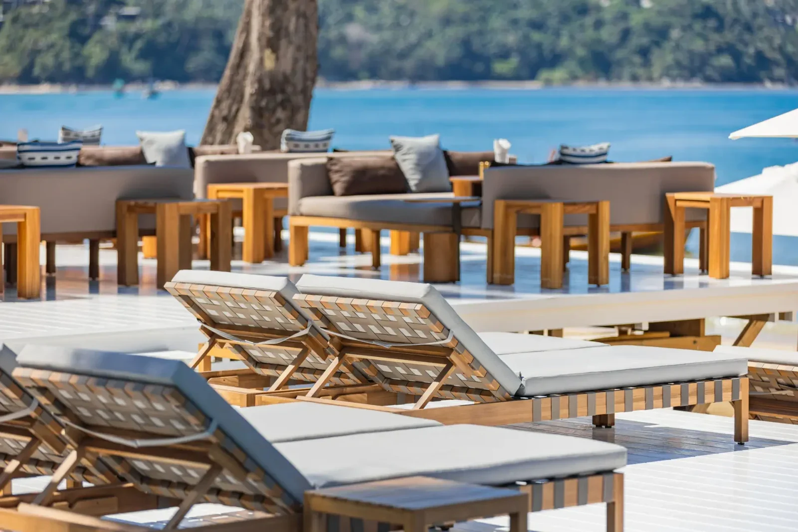 Деревянные шезлонги и диваны на террасе Catch Beach Club с видом на Банг Тао