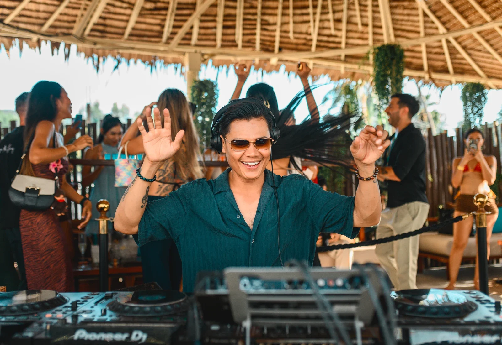 Диджей выступает за пультом под соломенным навесом Carpe Diem Beach Club