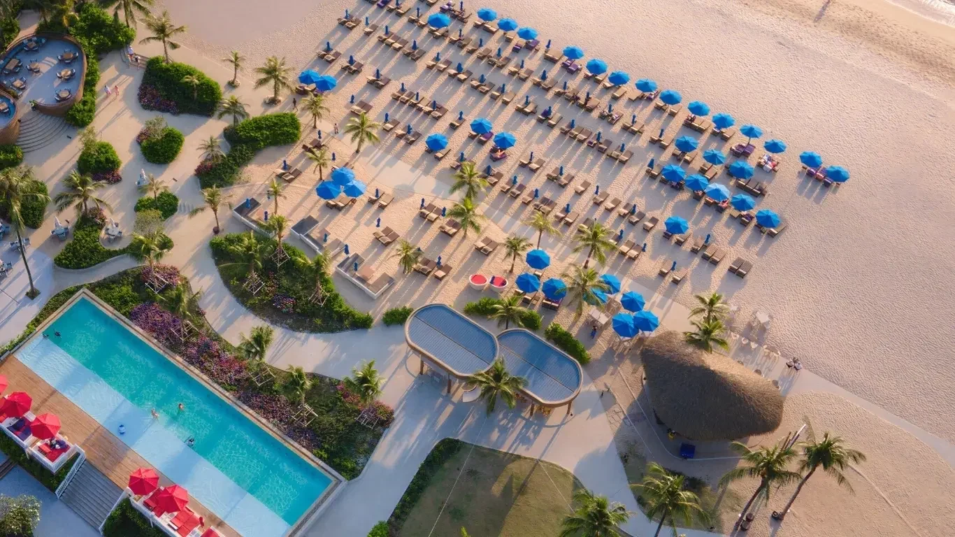 Бассейн XANA Beach Club и пляжные лежаки под синими зонтиками с высоты