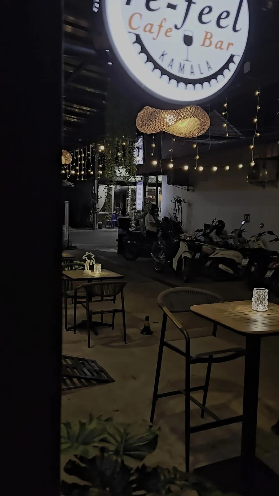 RIDE Phuket — фасад вечером. Фасад Re-Feel Lounge Bar, таблица Royal Enfield и стоящий у входа мотоцикл; карточка RIDE подтверждает совмещённую площадку.