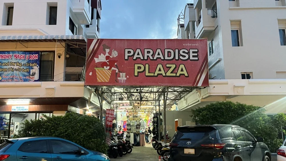 Вечерний вход в рынок Paradise Plaza с открытыми торговыми рядами и яркой вывеской