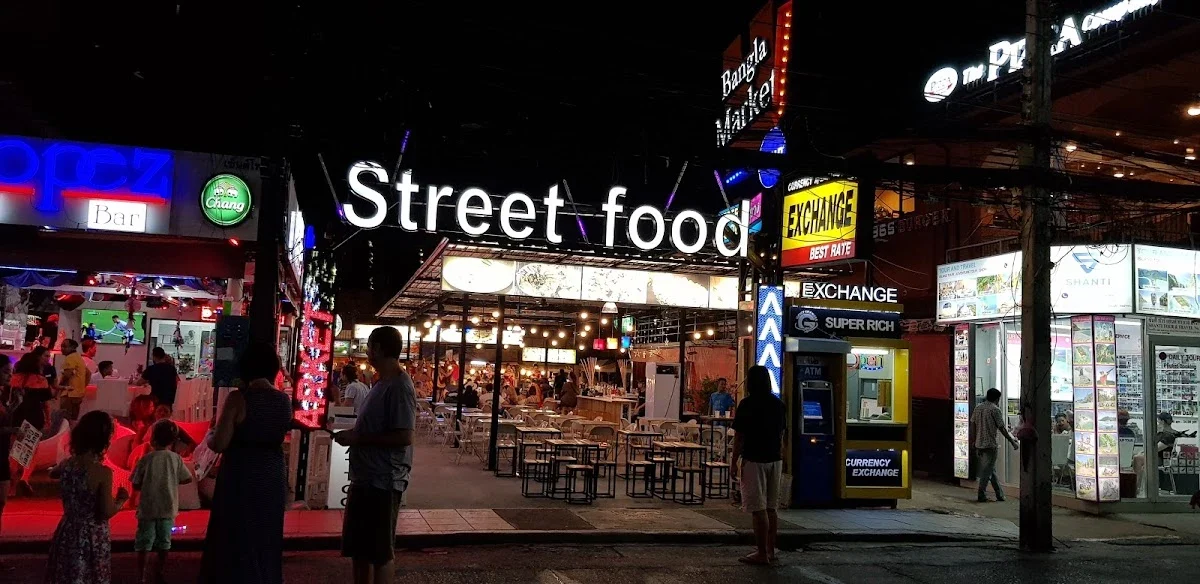 Освещённая вывеска Street Food над входом к прилавкам и столикам Bangla Night Market вечером