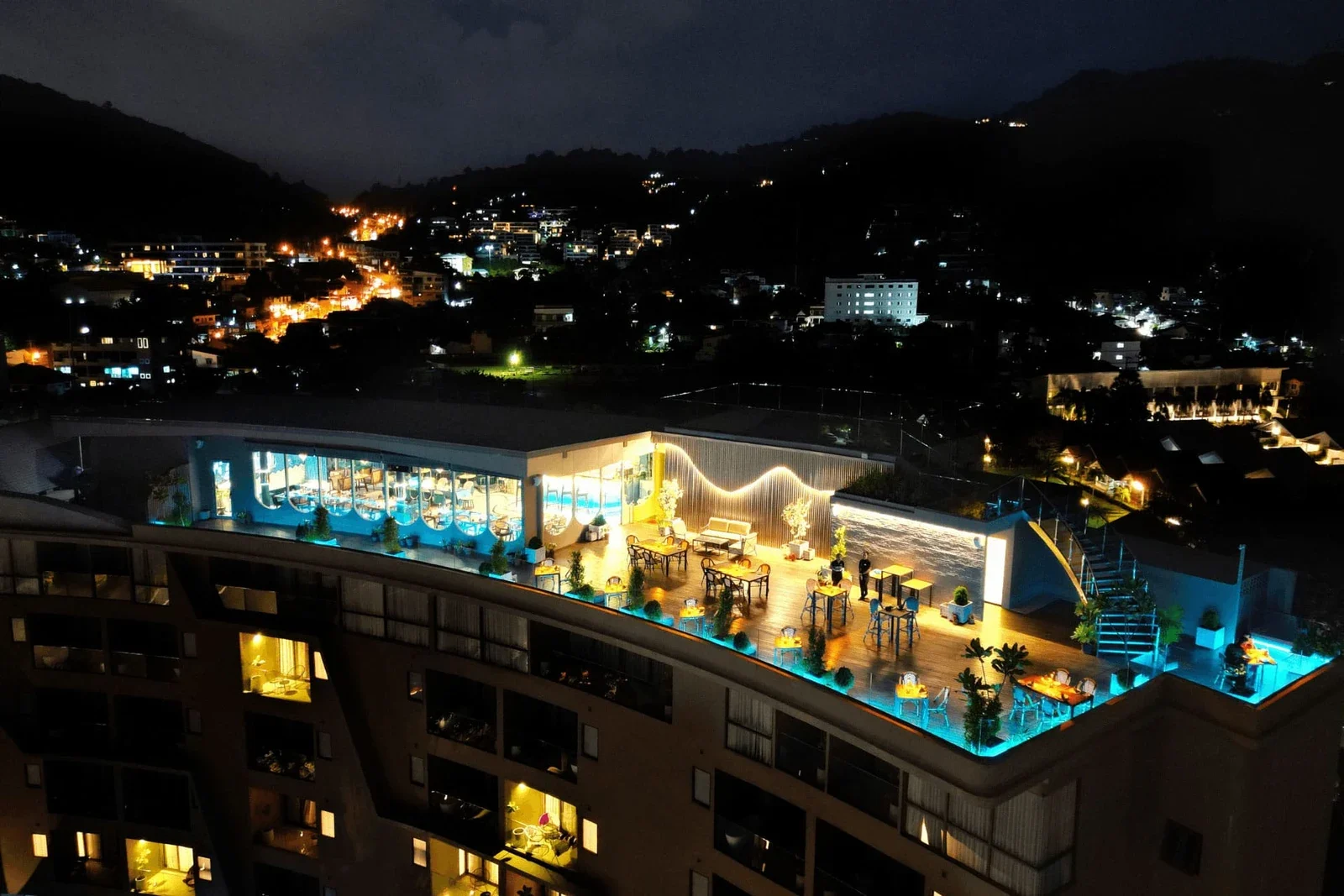 Крыша Moon Terrace Lounge ночью с высоты: подсвеченный ресторан на верхнем этаже здания над огнями Каты