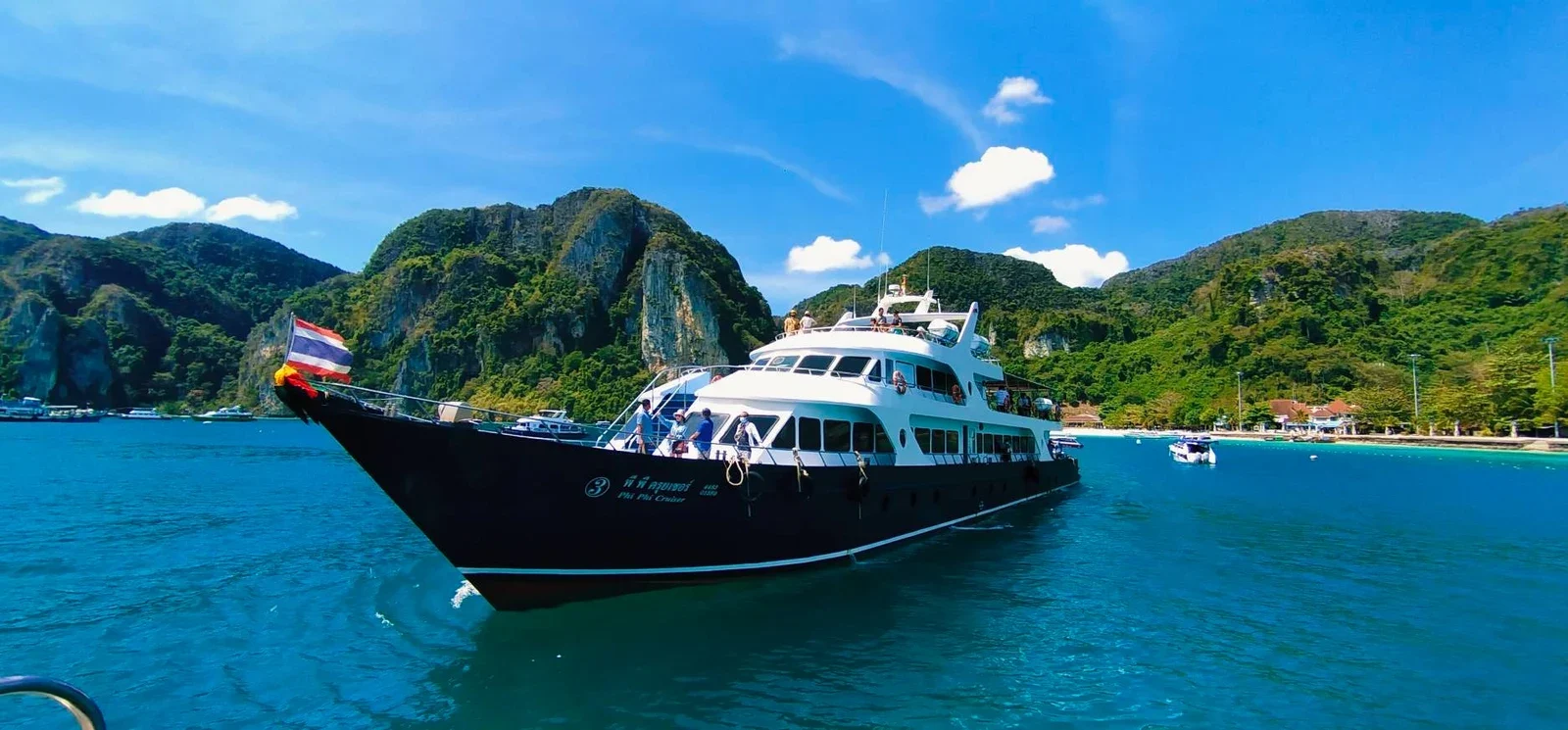 Фирменный круизер Phi Phi Cruiser с чёрным корпусом идёт у скалистых островов Пхи-Пхи.