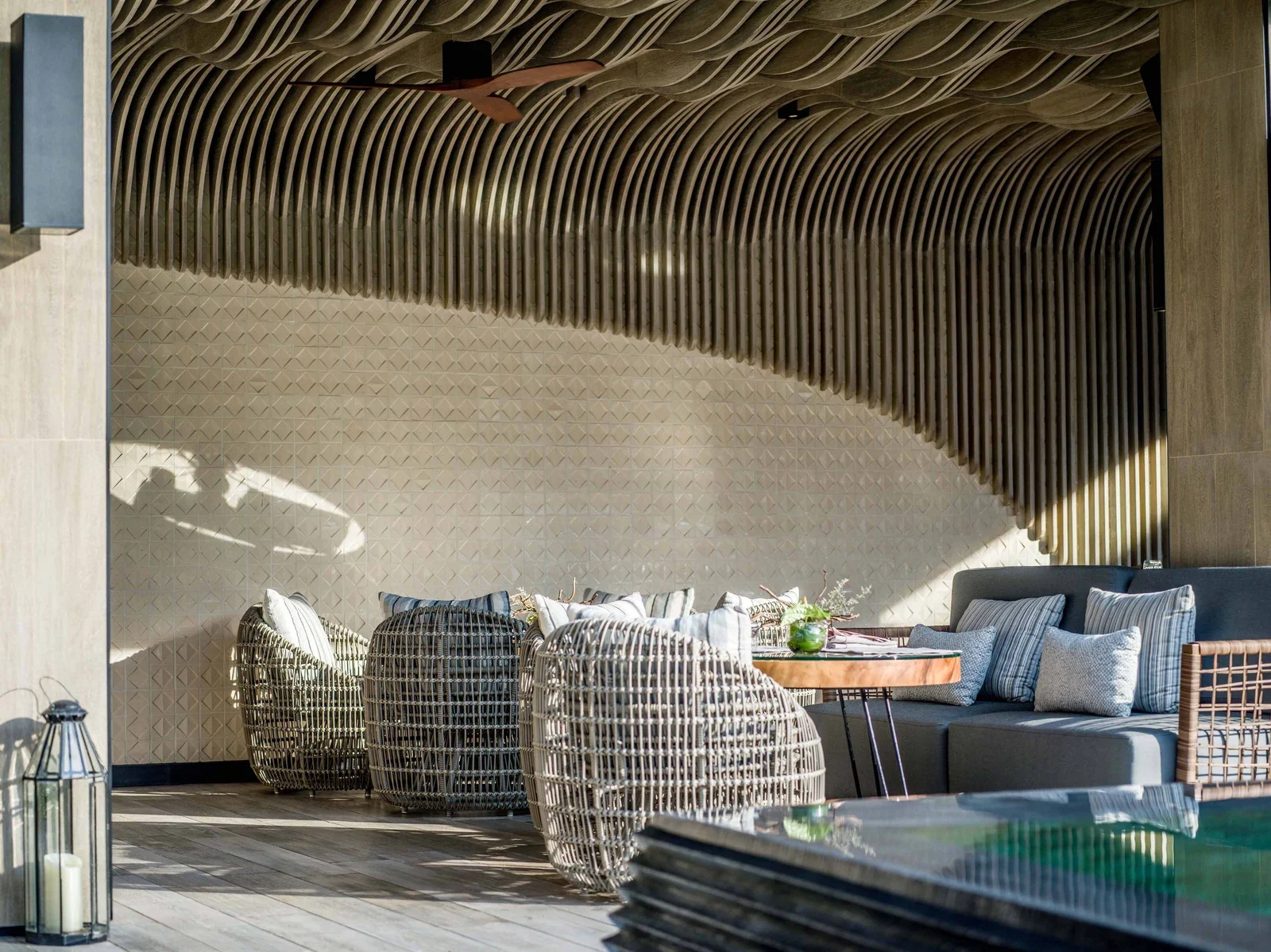 Лаундж Pine Beach Bar: плетёные кресла-коконы, диван с подушками и волнистый деревянный потолок под навесом