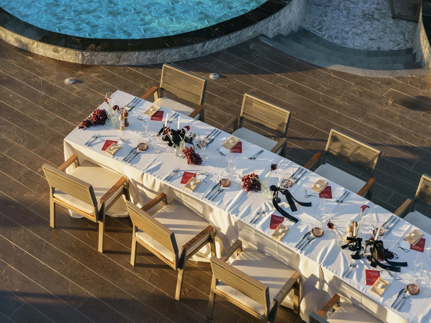 Длинный сервированный стол на террасе NORA Beach Club рядом с бассейном