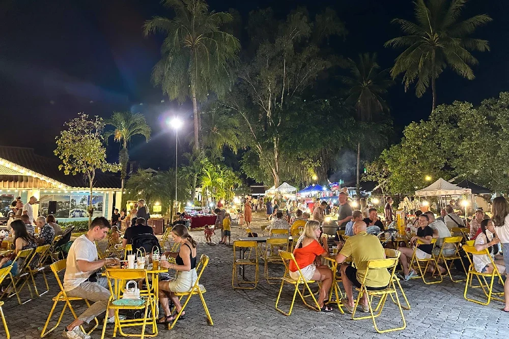 Вечерние столики и торговые палатки Laguna Lifestyle Night Market под пальмами у Laguna Grove.