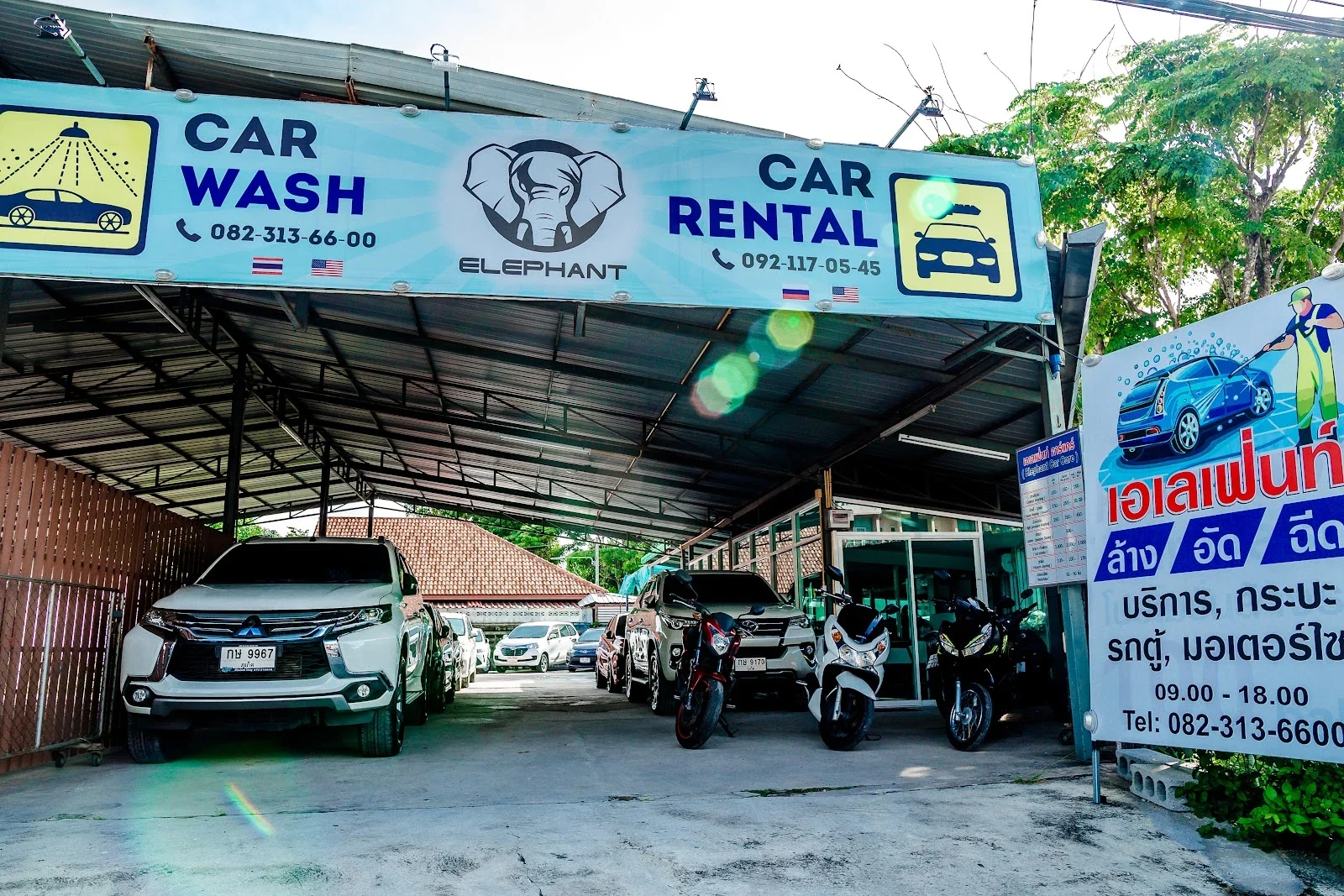 Вывеска Elephant Car Rental и автомойки над навесом офиса в Май Кхао, под навесом стоят внедорожник и байки.