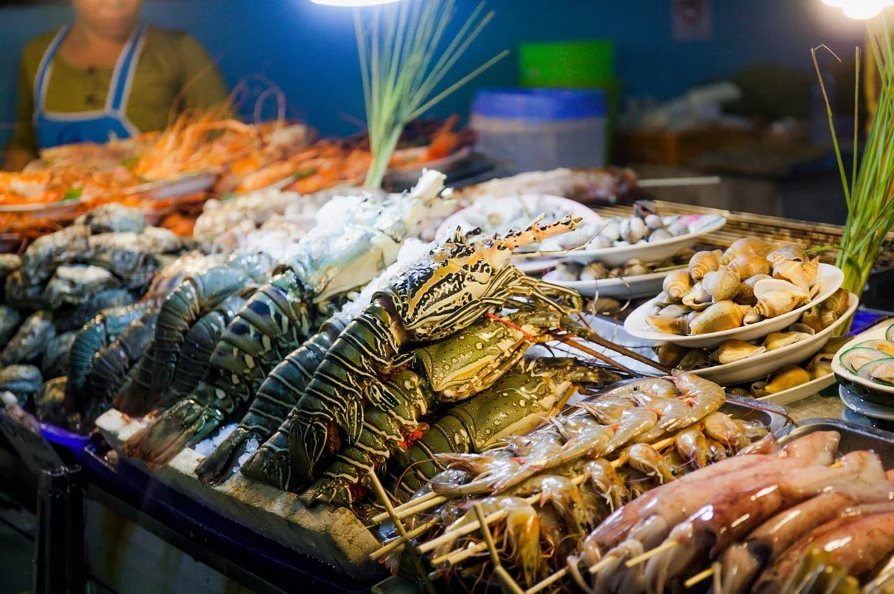 Прилавок с морепродуктами на рынке Нака: лобстеры, креветки и кальмары на льду рядом с грилем