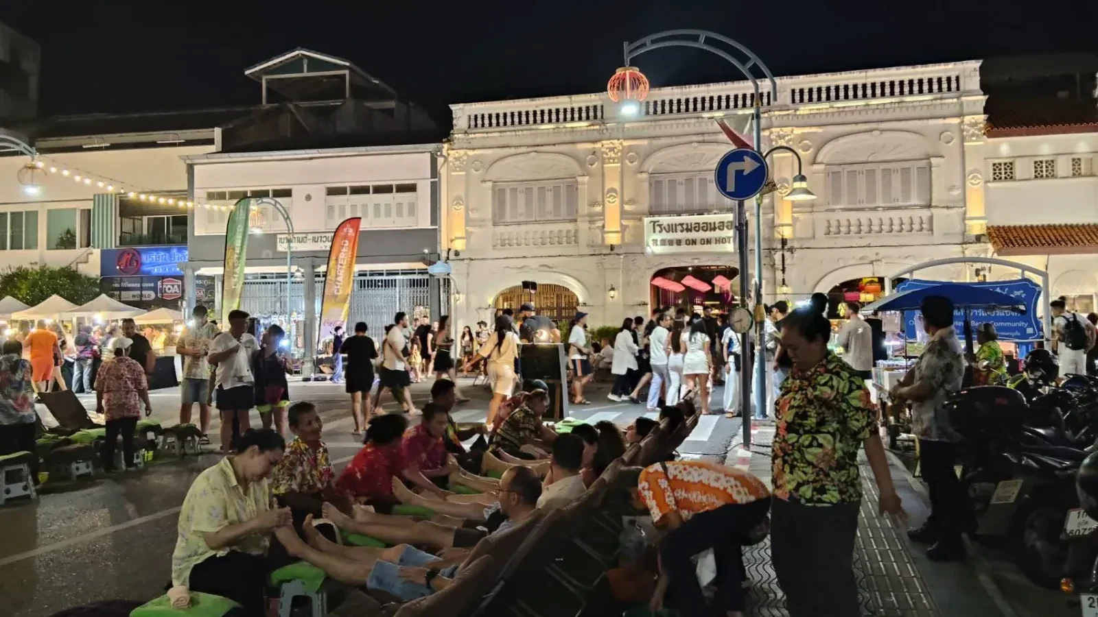 Посетители отдыхают на сеансе уличного массажа у торговых рядов Chartered Walking Street