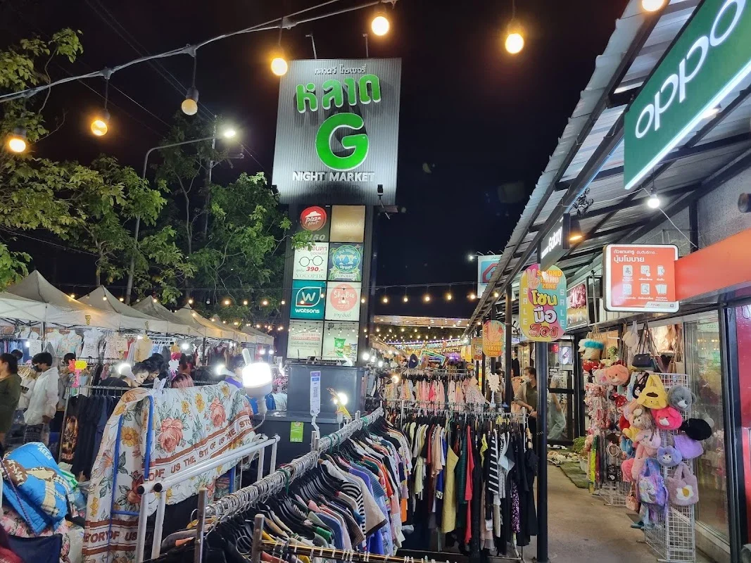Яркая вывеска G Night Market освещает вечерние ряды одежды и игрушек у Phuket Grocery