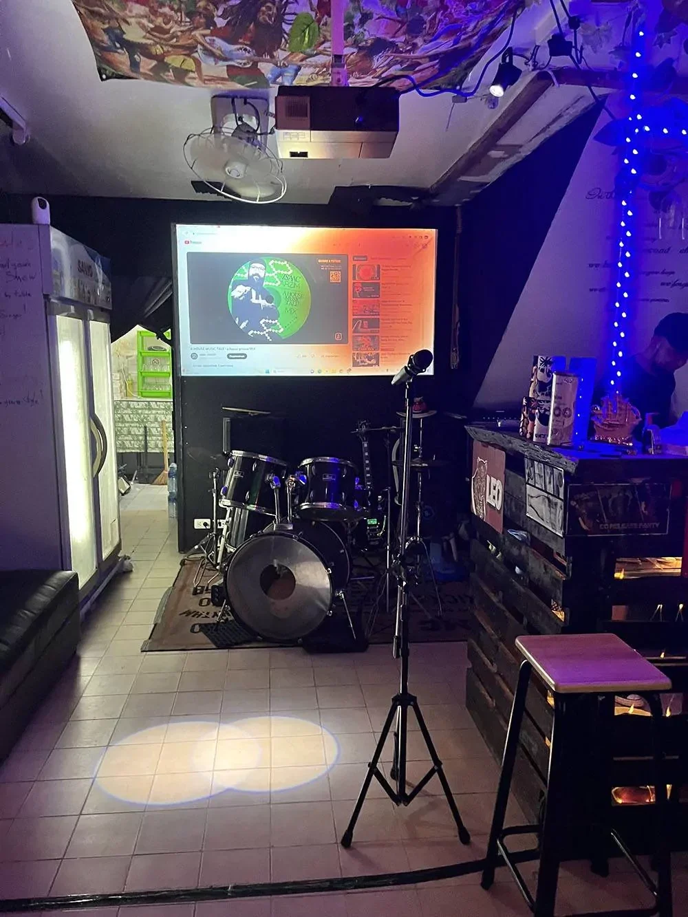Сцена Open Mic Bar с микрофоном, барабанами и проектором
