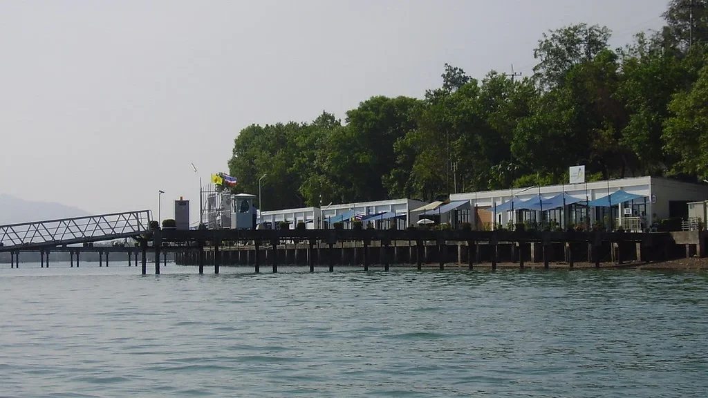 Пирс Phuket Yacht Haven с белыми зданиями и тентами на сваях, вид с воды.