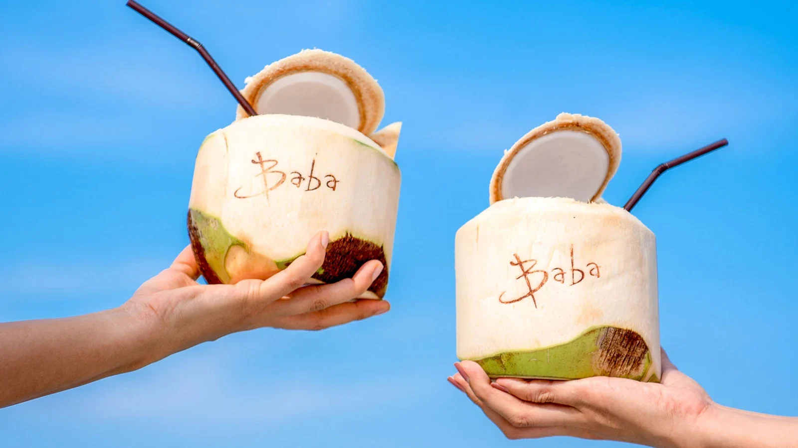 Свежие кокосы с надписью Baba в руках гостей Baba Beach Club Natai