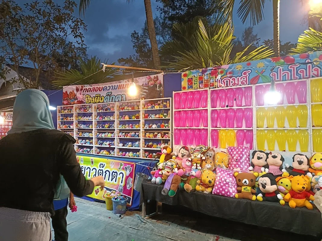 Игровые палатки Laguna Lifestyle Night Market с рядами шариков и мягкими игрушками среди вечерних огней.