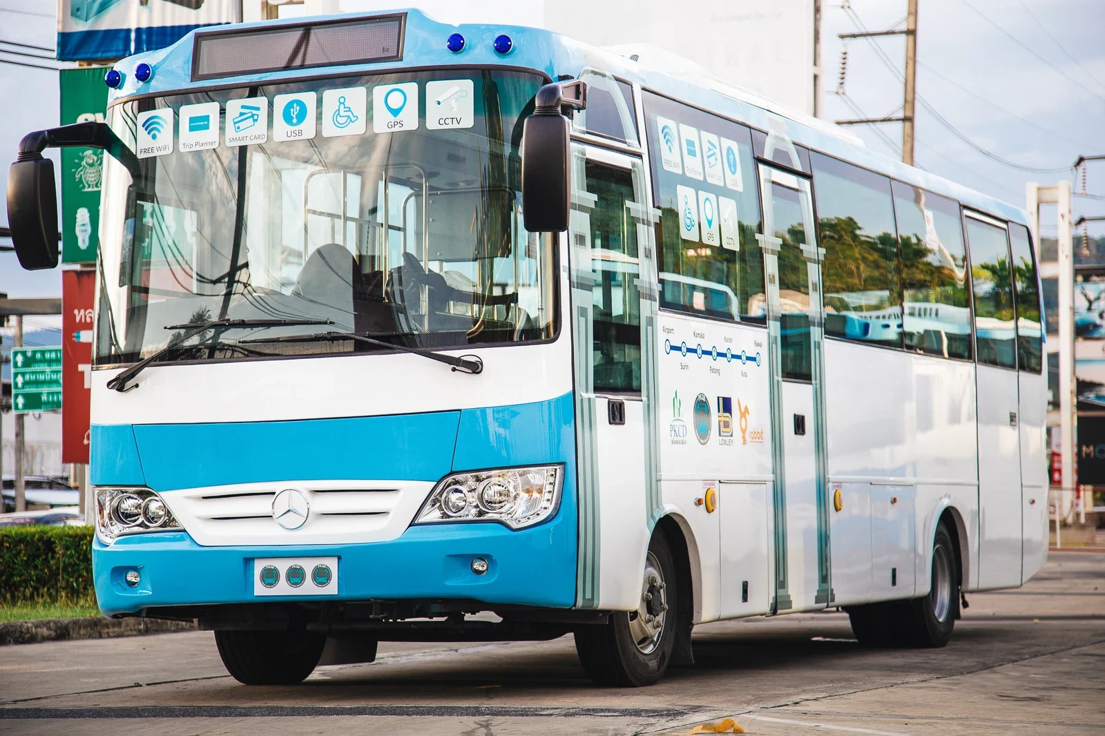 Бело-голубой Phuket Smart Bus стоит на дороге; на кузове видны схема маршрута и значки доступных сервисов.