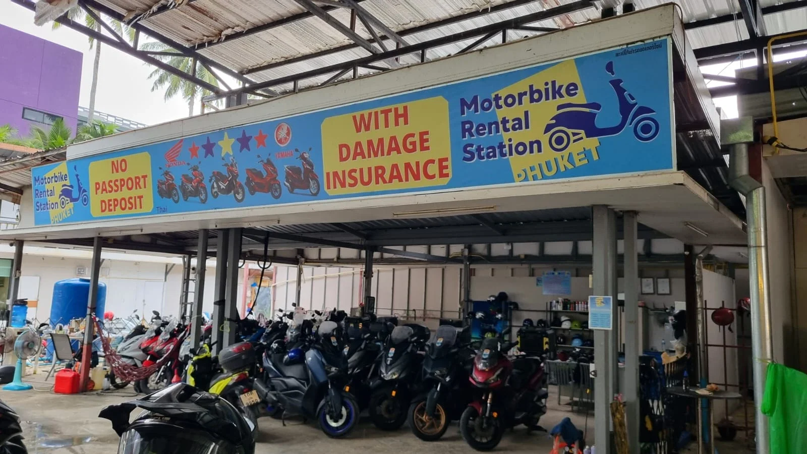 Навес с вывеской Motorbike Rental Station Phuket и плотный парк байков под ним на площадке проката