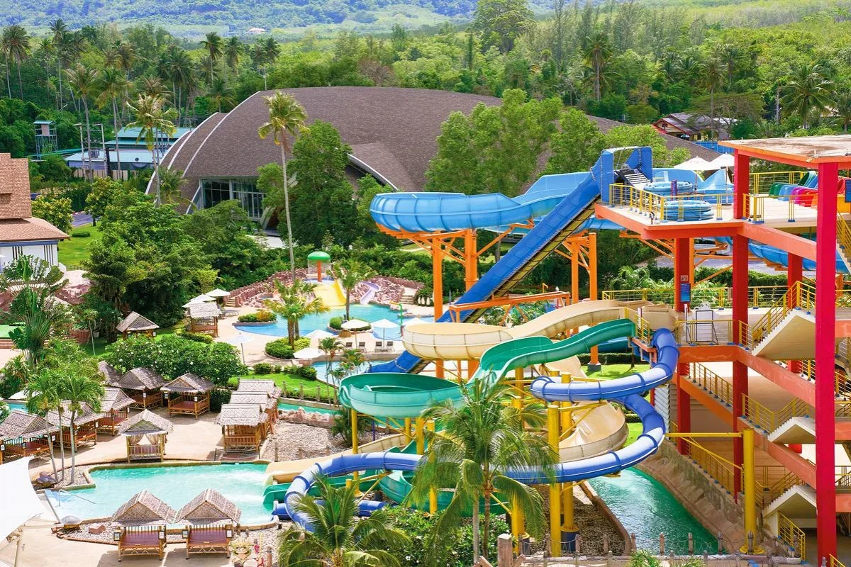 Вид сверху на разноцветные горки, бассейн и беседки Splash Jungle среди пальм
