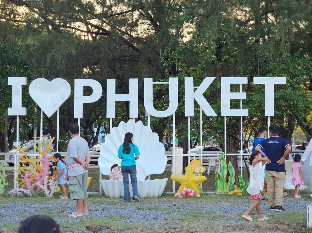 Арт-объект I LOVE PHUKET с кораллами и раковиной в парке Сапхан Хин, вокруг гуляют семьи с детьми.