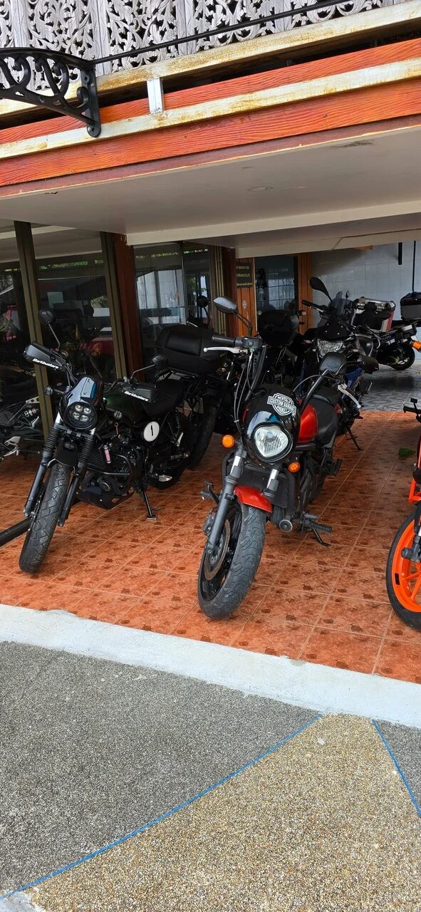 Custom Garage — площадка у входа. Крытая площадка перед стеклянным входом; мотоциклы с наклейкой Custom Garage, деревянный фасад.