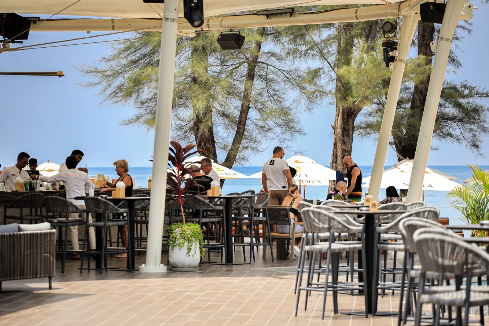 Обеденный зал NORA Beach Club под открытым навесом с видом на море