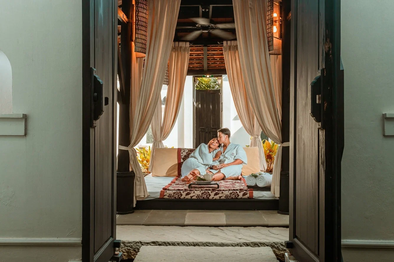 Двое гостей в халатах на диване за занавесями в павильоне спа JW Marriott Phuket