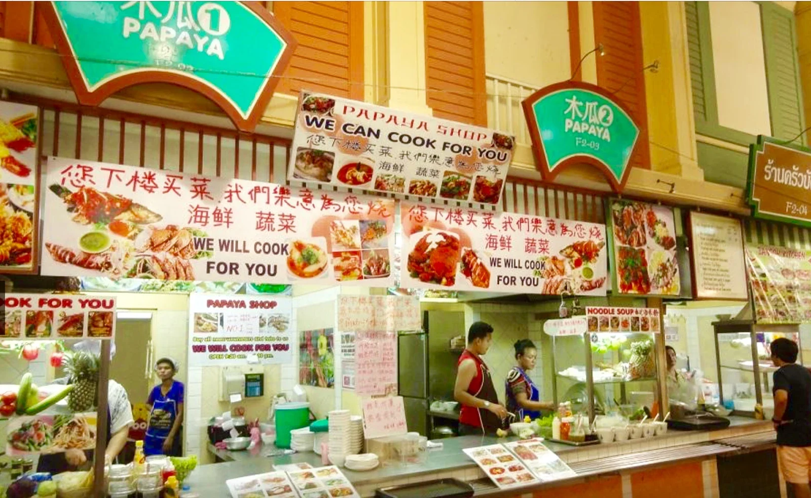 Прилавок Papaya Shop в фудкорте над рынком Banzaan: вывески «We can cook for you», повара за стойкой